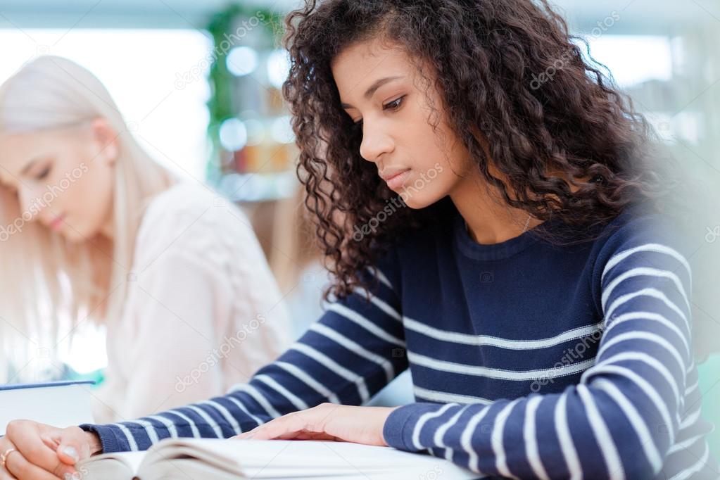 Female student reading book in classroom