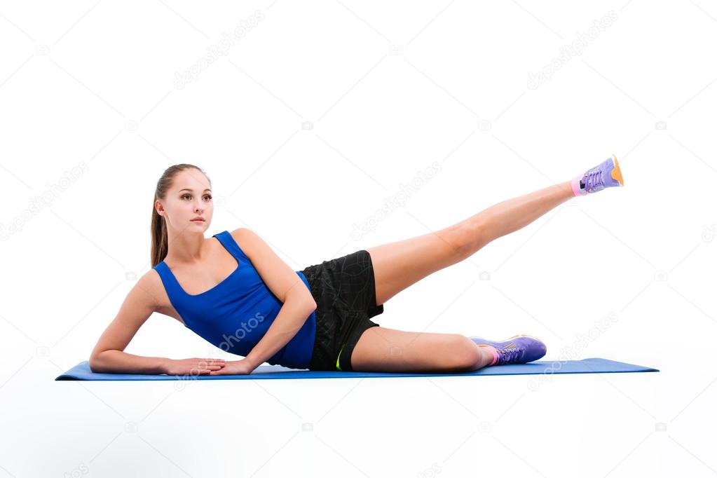 Young sportswoman in sportwear doing exercises for legs