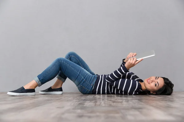 Vrouw liggend op de vloer met tablet pc — Stockfoto