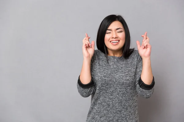 Азиатская девушка держит пальцы скрещенными и глаза закрытыми — стоковое фото