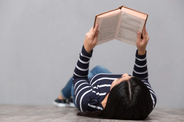 Jovem mulher mentindo e lendo um livro — Fotografia de Stock