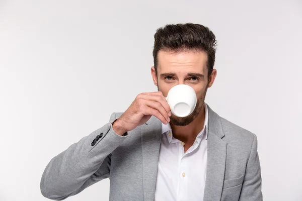 Geschäftsmann trinkt Kaffee und blickt in die Kamera — Stockfoto