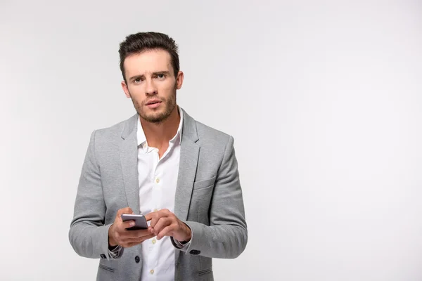 Businessman using smartphone and looking at camera — Stock Photo, Image