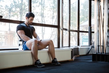 Fitness adam windowcill üzerinde oturan müzik dinlemek