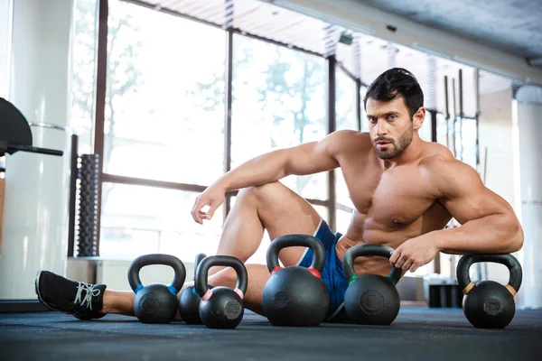 Athletic man sitting near kettle balls — Stock Photo, Image