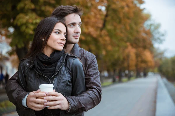 Couple with coffee looking away outdoors — Stock Photo, Image