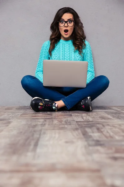 Έκπληκτος γυναίκα κάθεται στο πάτωμα με laptop — Φωτογραφία Αρχείου
