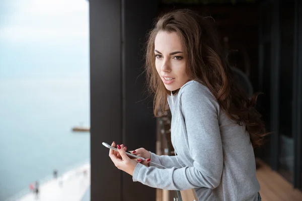 Mujer bonita escuchando música de pie en el balcón — Foto de Stock