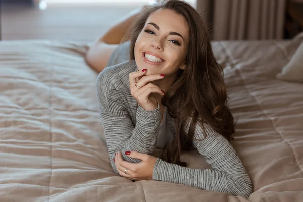 Felice giovane donna sdraiata sul letto — Foto Stock