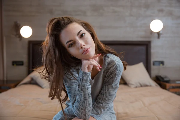 Smuk kvinde sidder på sengen - Stock-foto