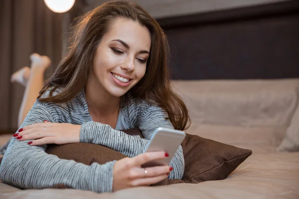 Mujer acostada en la cama y usando smartphone —  Fotos de Stock