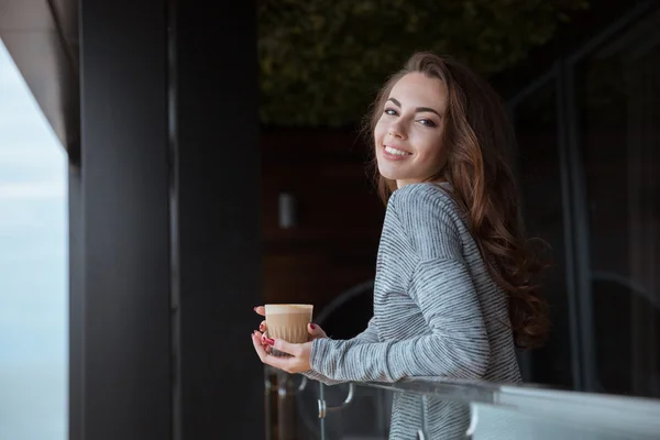 Frau steht mit Kaffee auf dem Balkon — Stockfoto