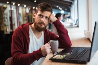 Yakışıklı olan kahve içme ve dizüstü bilgisayar kullanarak