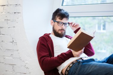 Yakışıklı delikanlı pencere pervazına üzerinde okuma