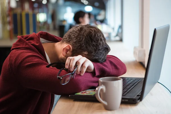 Cansado homem segurando óculos enquanto dormia na mesa do escritório — Fotografia de Stock