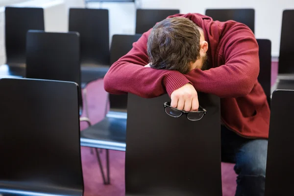 Kimerült fiú gazdaság szemüveg, és alszik, konferencia terem — Stock Fotó