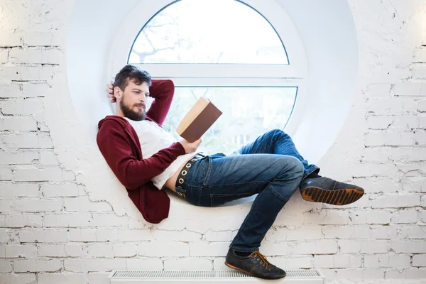 Étudiant couché et lisant sur le rebord de la fenêtre — Photo