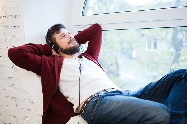 Young man lying and relaxing on sill of round window