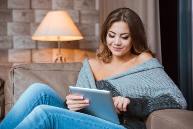 Tablet bilgisayar kanepede kullanan kadın