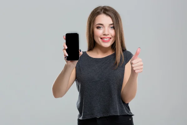 Mujer mostrando pantalla de teléfono inteligente en blanco y pulgar hacia arriba — Foto de Stock