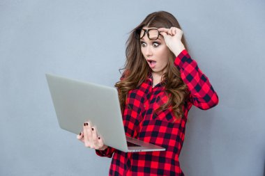 Portrait of shocked girl with opened mouth using laptop clipart