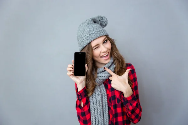 Donna ammiccando e puntando il dito sullo schermo dello smartphone vuoto — Foto Stock