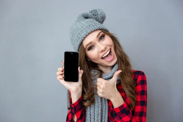 Woman showing blank smartphone screen and thumb up
