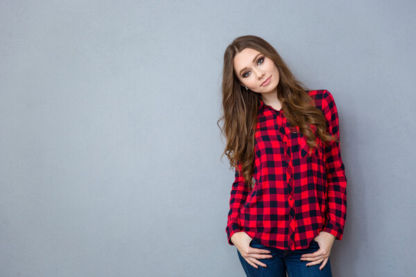 Young woman in plaid shirt posing on gray background