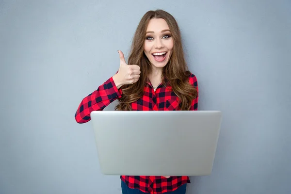 Glad tjej håller laptop och visar tummen upp — Stockfoto