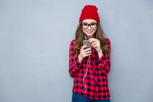 Leende kvinna med smartphone med hörlurar — Stockfoto