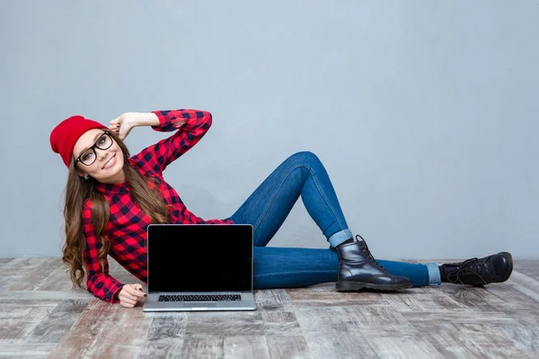 Donna sdraiata sul pavimento e mostrando schermo del computer portatile vuoto — Foto Stock