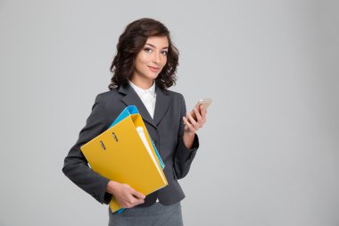 Cep telefonu ve holding bağlayıcılar kullanan genç ve güzel iş kadın