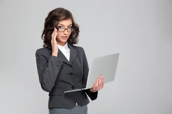 Молодая деловая женщина держит ноутбук и трогает очки — стоковое фото