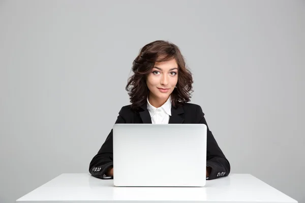Sonriendo hermosa mujer joven sentada y usando el ordenador portátil — Foto de Stock