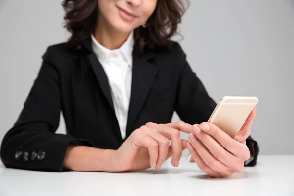 Young smiling woman sitting and using cellphone — Stock Photo, Image