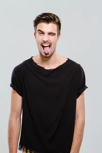 Young funny guy winking and sticking out his tongue — Stock Photo, Image