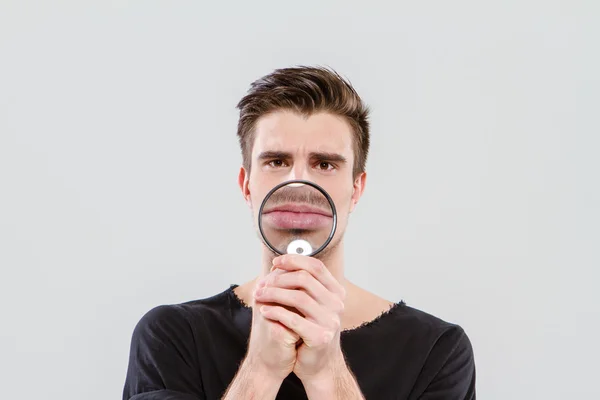 Funny man playing tricks using magnifying glass — Stock Photo, Image