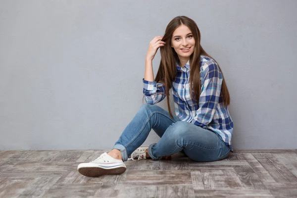 Šťastná mladá žena sedí na podlaze — Stock fotografie