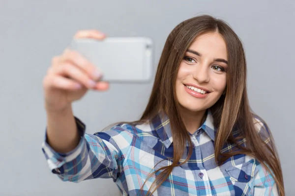 Pretty young woman smiling and shooting herself — Stock Photo, Image