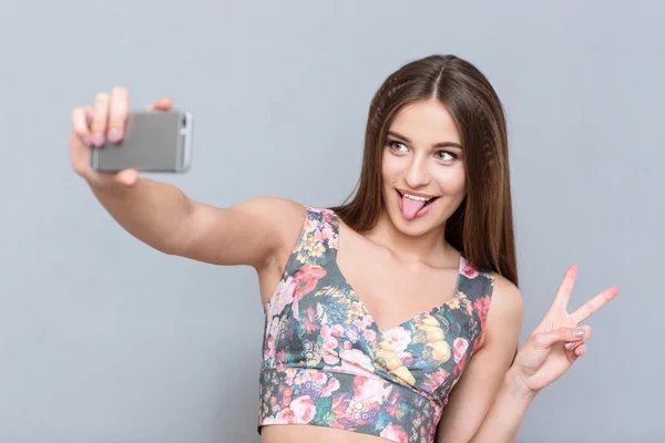 Piękna młoda kobieta co selfie i pokazując język — Zdjęcie stockowe