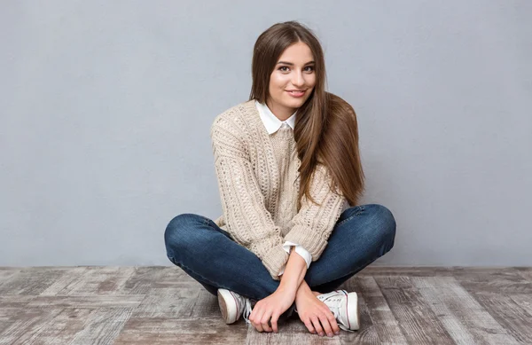 Улыбающаяся девушка, сидящая на полу со скрещенными ногами — стоковое фото