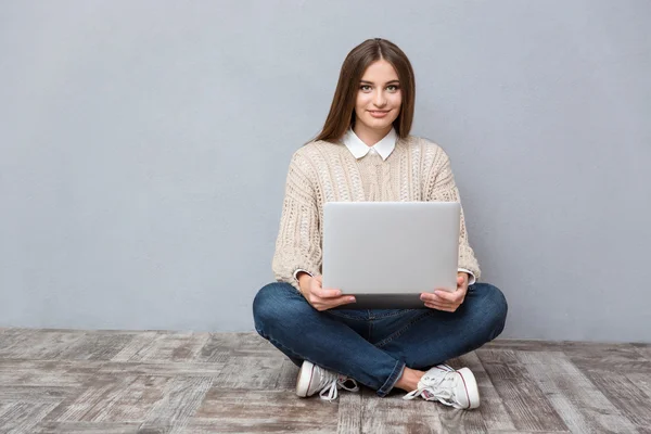 Ung självsäker kvinna använder laptop sittin på trägolv — Stockfoto