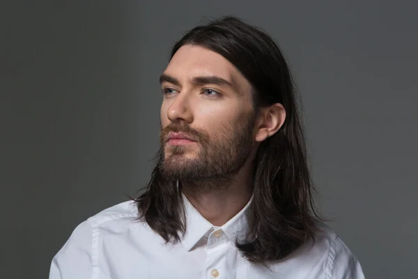 Serious man with beard and long hair looking away — Stock Photo, Image