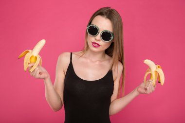 Pretty sensual young female holding two bananas