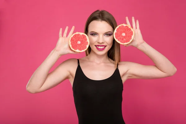 Щаслива усміхнена дівчина позує з двома половинками грейпфрута — стокове фото