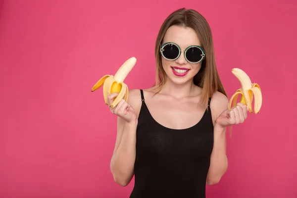 Portrait of positive attractive young woman holding two bananas — Stock fotografie