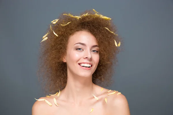 Joyeux joyeux jeune femme avec des pétales sur les cheveux et les épaules — Photo