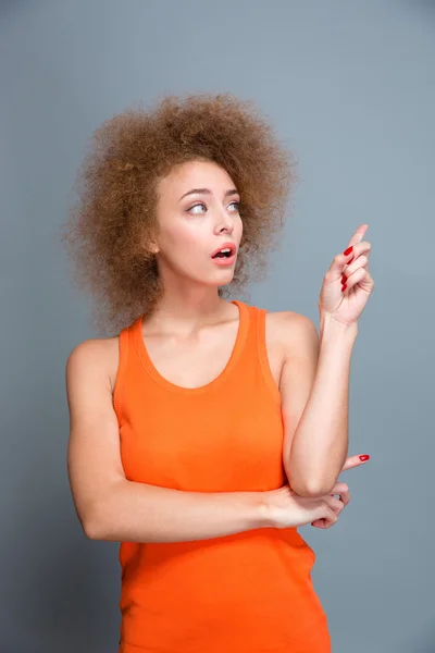 Mujer bonita asombrada apuntando lejos en copyspace — Foto de Stock