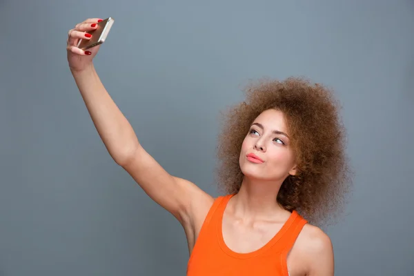 Beautiful young curly woman making selfie using cellphone — Zdjęcie stockowe