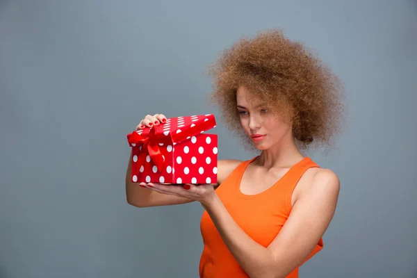 Attractive pretty curly young woman opening present — Φωτογραφία Αρχείου